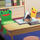 Two chairs, one green and one yellow, with smiling frog faces on their backrests.